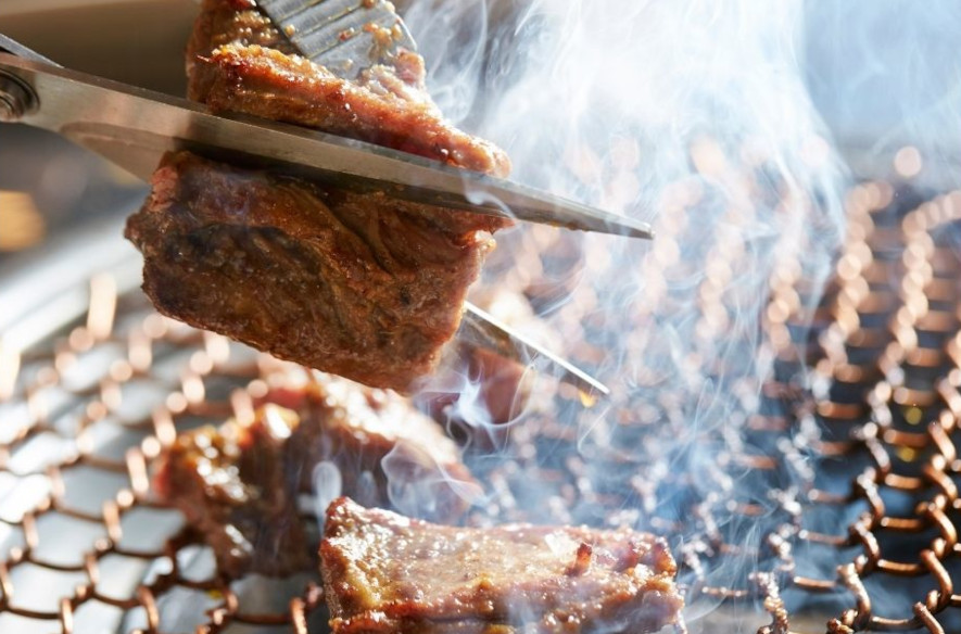 Klipper kött med sax ovanför grillen